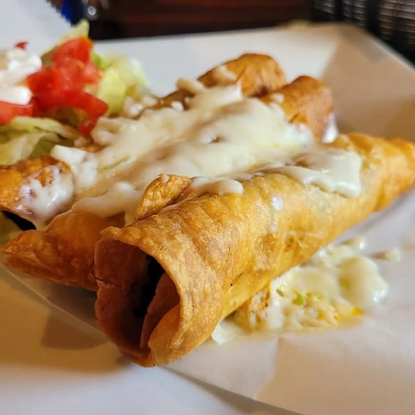 Crispy taquitos topped with melted cheese, lettuce, tomatoes, and sour cream at Señor Jose's.